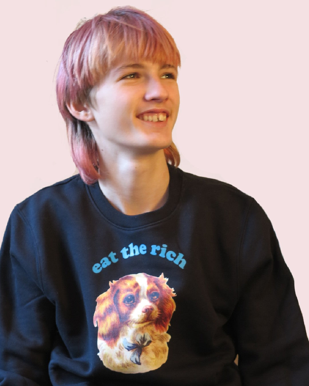 Lächelnde Person trägt Vintage-Illustration eines Cocker-Spaniel-Welpen mit ‚Eat the Rich‘ Typografie auf Bio-Sweater