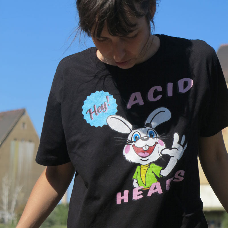 Retro-Design eines winkenden Hasen, Aufschrift: Hey Acid Heads, schwarzes T-Shirt, getragen von Model vor blauem Himmel