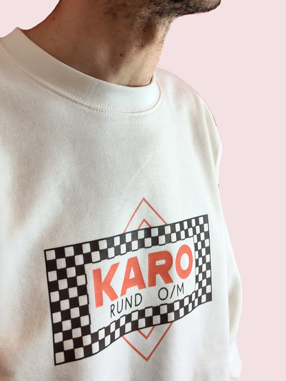 Person trägt Sweater mit Print des minimalistischen Re-Design der legendären „KARO“
DDR Kippen. O/M steht für: ohne Mundstück. Bio. Fair. Vegan.